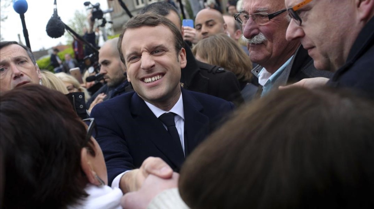 Centrist candidate Emmanuel Macron shakes hands with a supporter after casting his ballot in the first round of the French presidential election in le Touquet northern France Sunday April 23 2017 AP Photo Thibault Camus